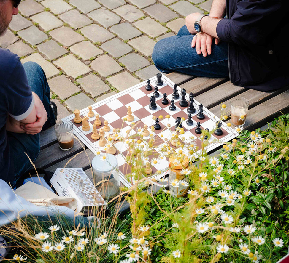 Zwei Personen sitzen auf einer Bank und spielen Schach.